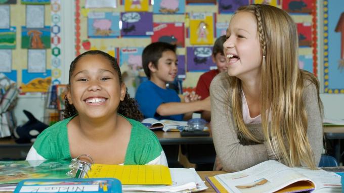 Két iskoláslány ADHD-val ülő-on iskolapad és nevetve